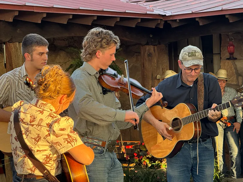 A camper and instructor play fiddle and guitar together