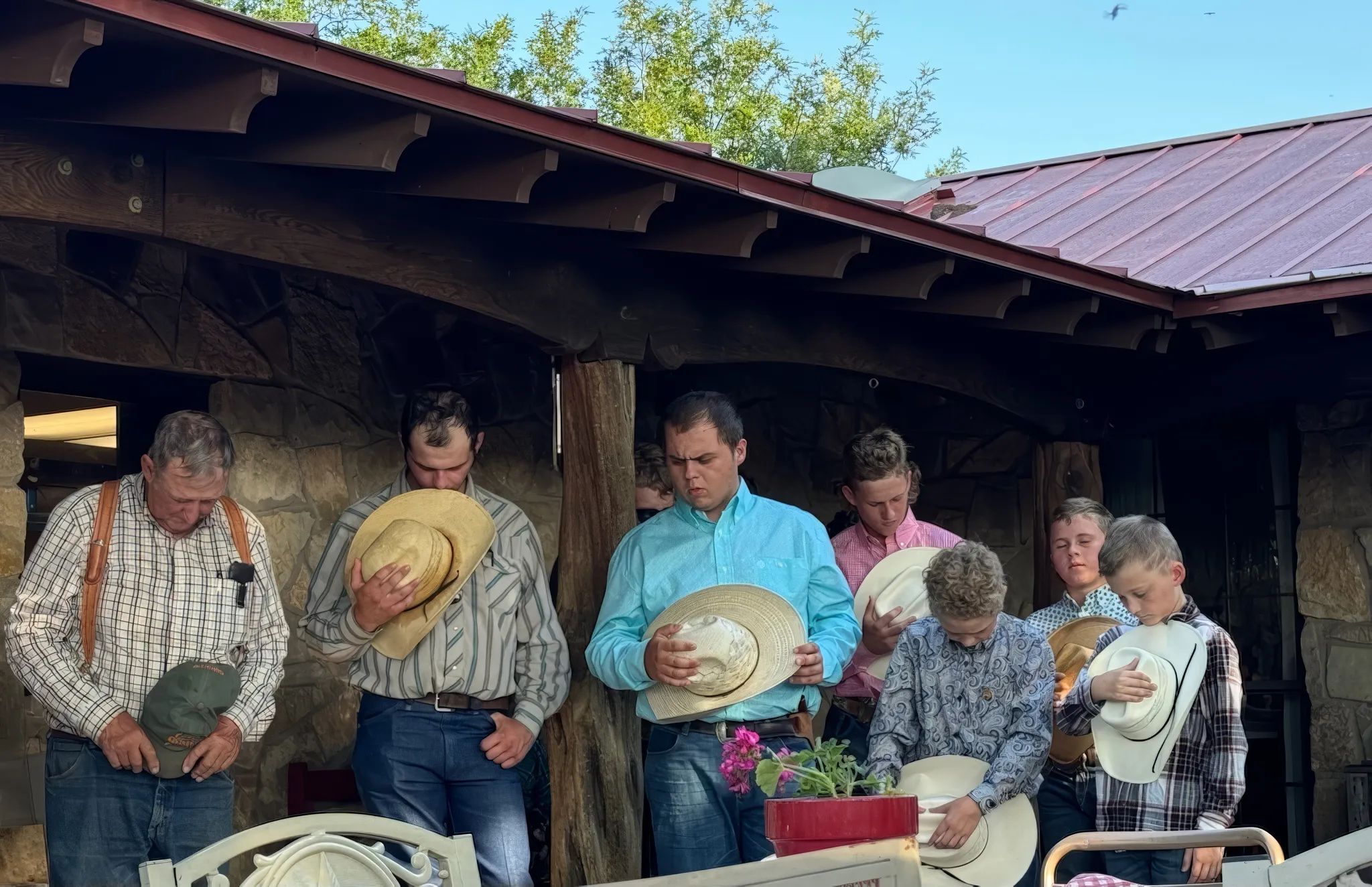 Campers and staff gather on the ranch porch, hats in hand